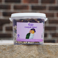 Container of Feather Chef Caique Treats with a bird on the label against a brick wall background